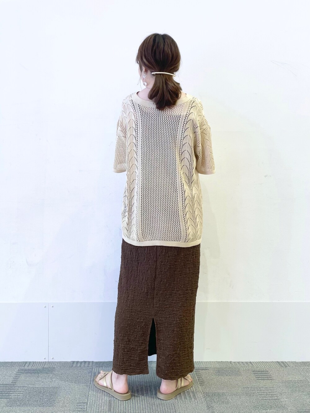 ゴールド系のサンダル、ブラウン系のスカート、ブラック系のショルダーバッグを着用したレディースの夏コーディネートの2枚目の写真