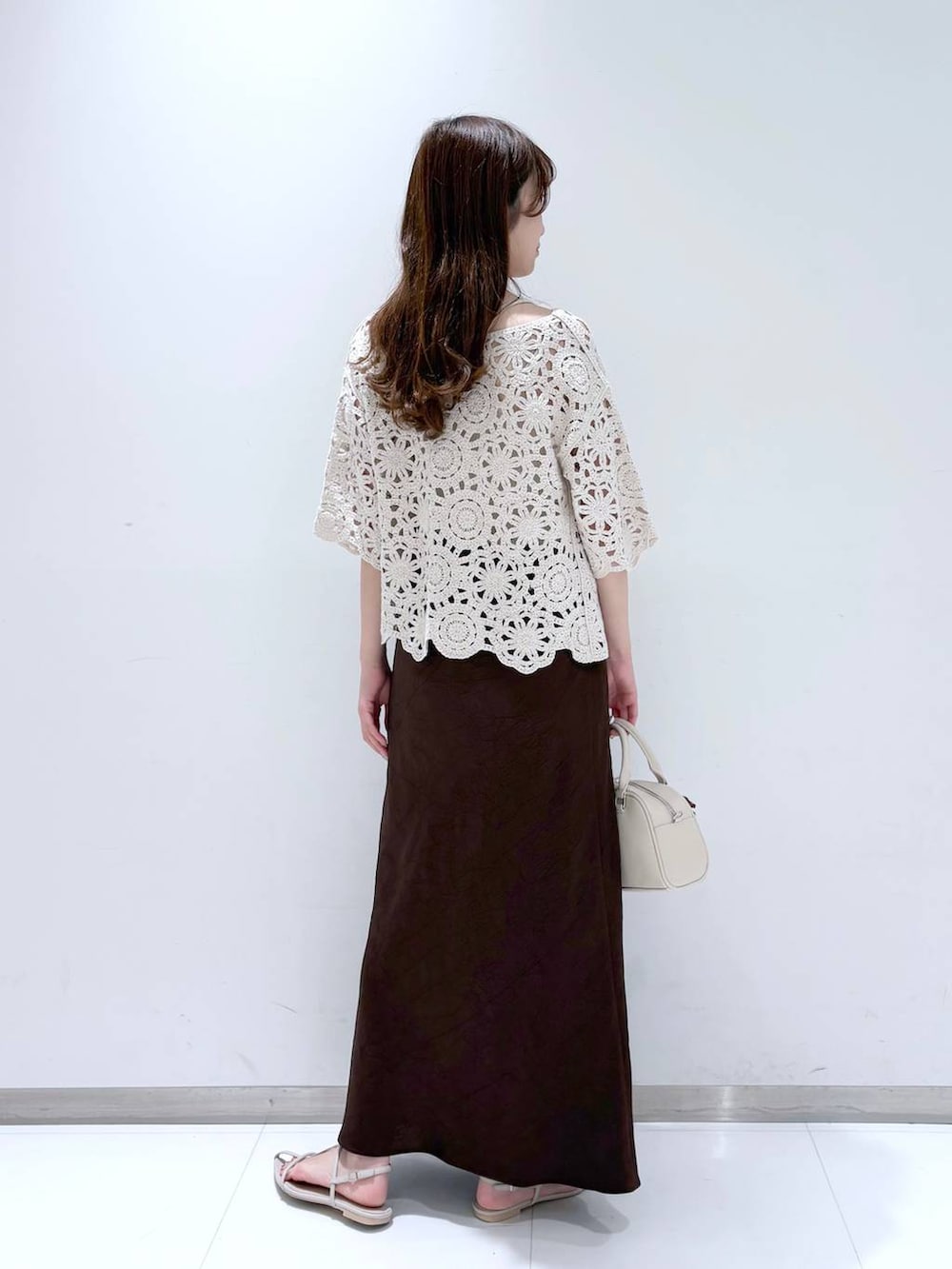 ホワイト系のTシャツ/カットソー、ホワイト系のサンダル、ブラウン系のスカートを着用したレディースの春コーディネートの3枚目の写真