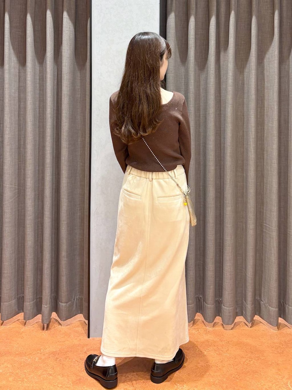 ゴールド系のショルダーバッグ、ホワイト系のスカート、ブラック系のローファーを着用したレディースの秋コーディネートの4枚目の写真