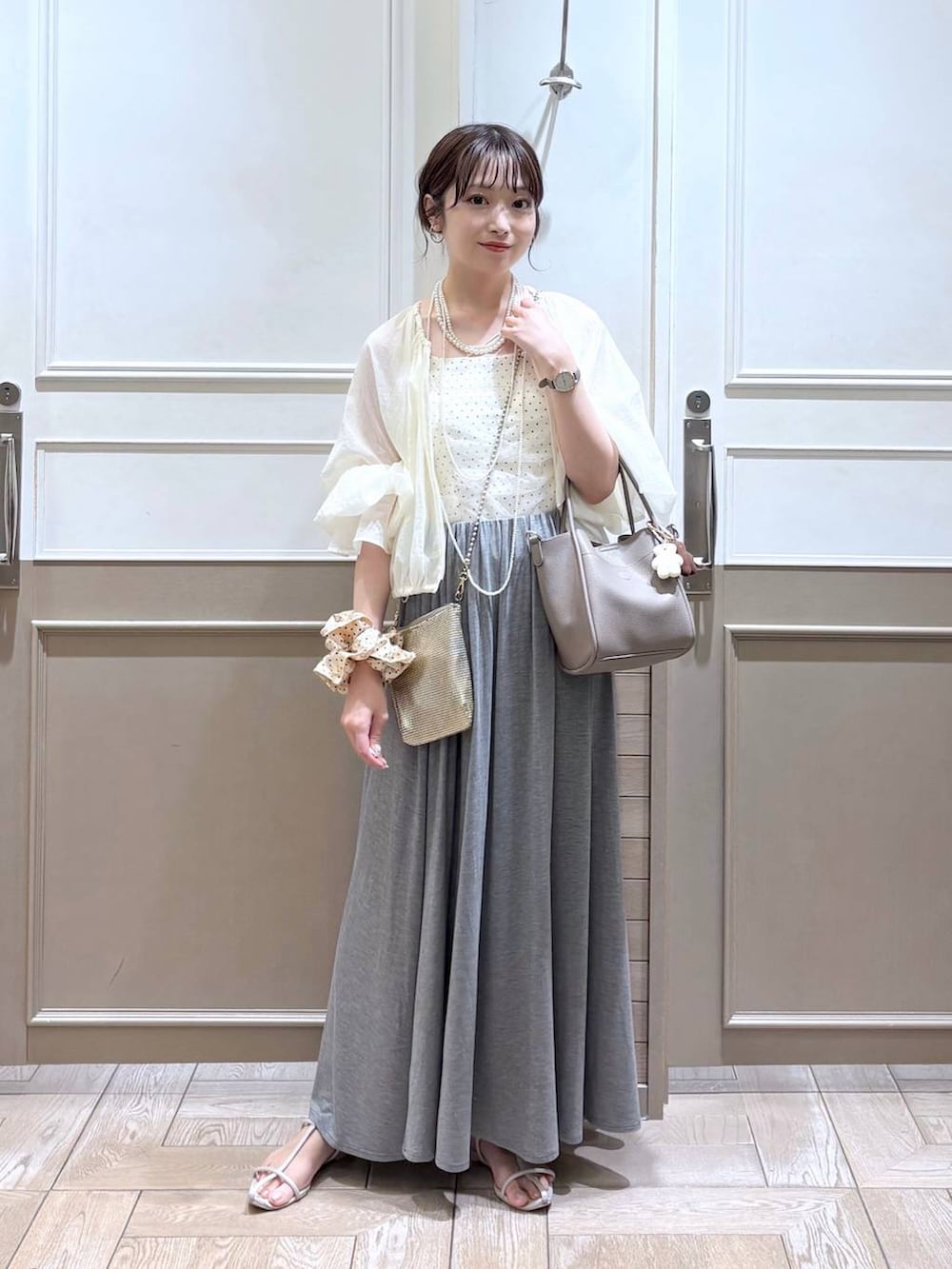 ゴールド系のショルダーバッグ、ホワイト系のサンダル、ホワイト系のブルゾンを着用したレディースの夏コーディネートの3枚目の写真