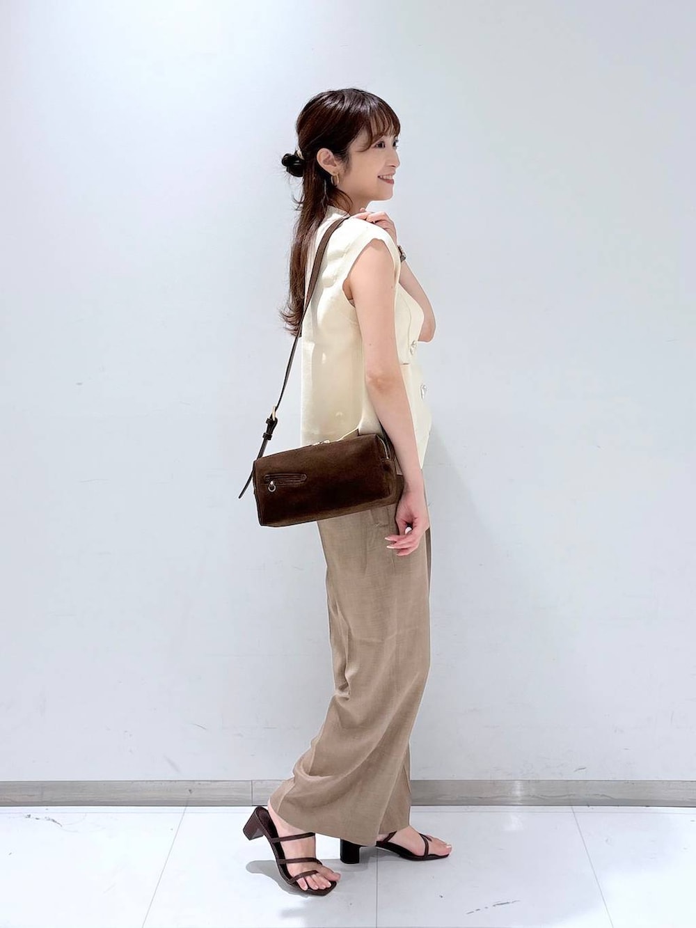 ホワイト系のTシャツ/カットソー、ブラウン系のサンダル、ベージュ系のスラックスを着用したレディースの夏コーディネートの3枚目の写真