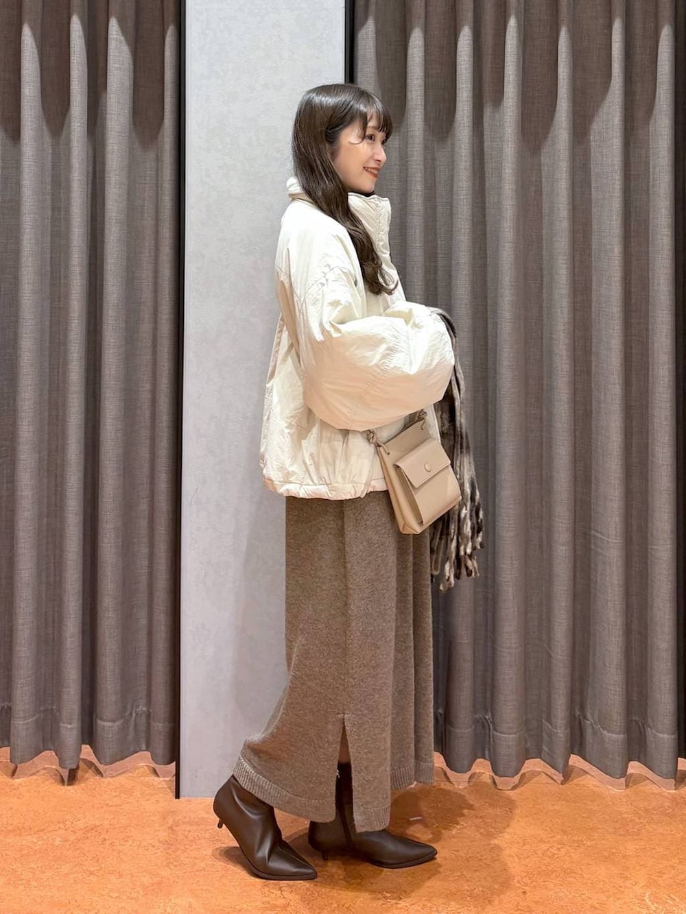 ホワイト系のその他アウター、ブラウン系のブーツ、ブラウン系のワンピースを着用したレディースの秋コーディネートの2枚目の写真