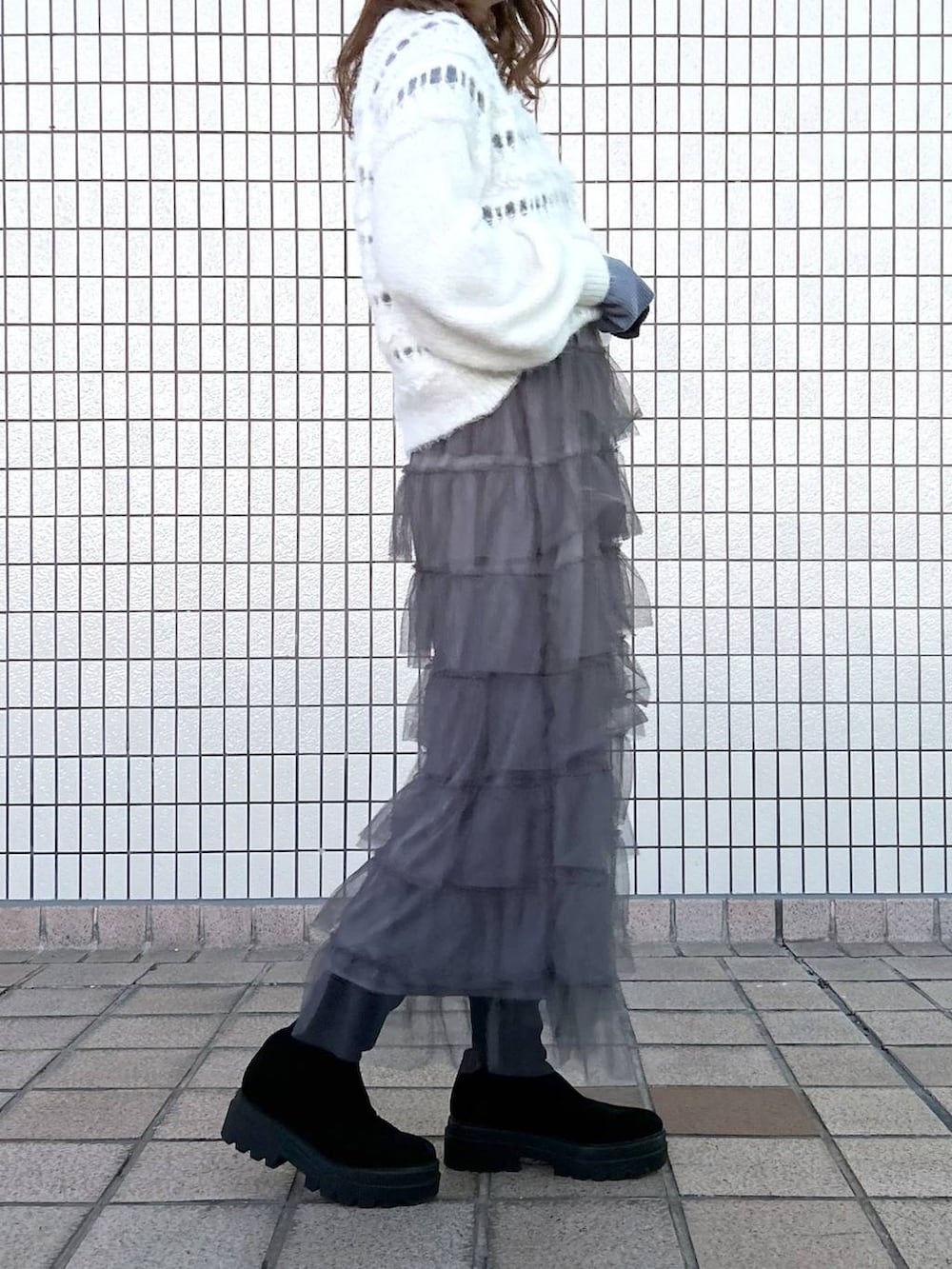 ブラック系のブーツ、グレー系のスカート、ホワイト系のニット/セーターを着用したレディースの冬コーディネートの2枚目の写真