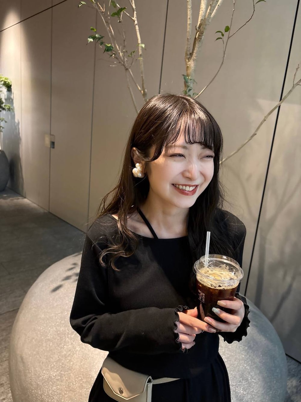 ブラック系のスカート、ベージュ系のボディバッグ/ウエストポーチ、ブラック系のパンプスを着用したレディースの春コーディネートの3枚目の写真