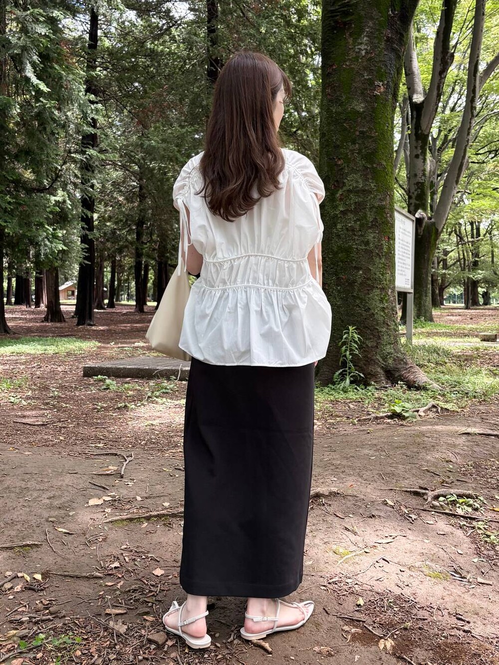 ホワイト系のTシャツ/カットソー、ホワイト系のサンダル、ブラック系のスカートを着用したレディースの夏コーディネートの3枚目の写真