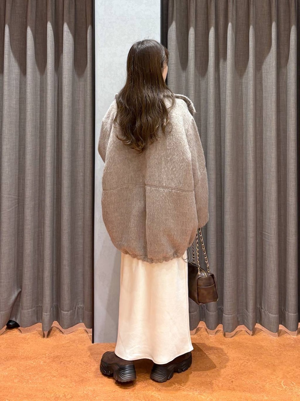 ブラウン系のブーツ、ホワイト系のスカート、ホワイト系のその他アウターを着用したレディースの冬コーディネートの4枚目の写真