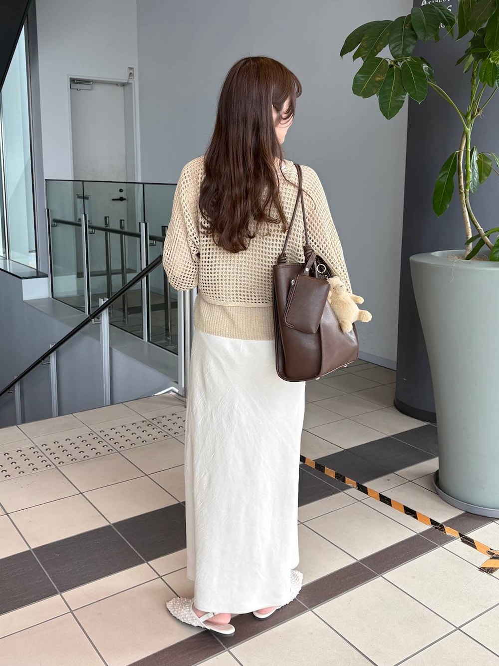 ホワイト系のスカート、ブラウン系のトートバッグ、ホワイト系のパンプスを着用したレディースの春コーディネートの2枚目の写真