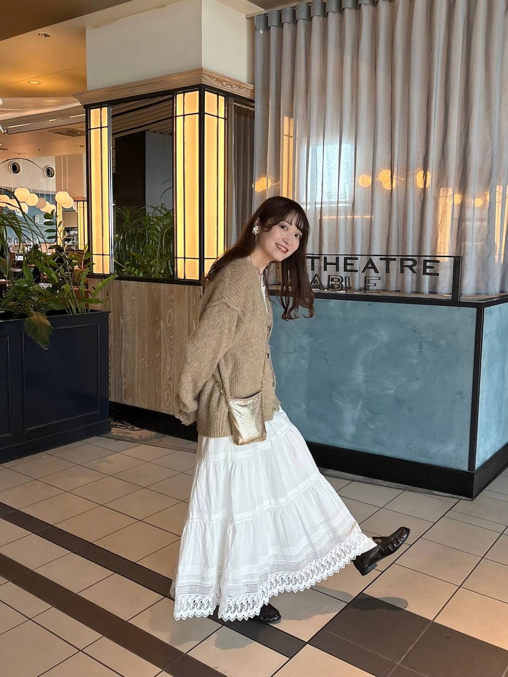 ゴールド系のショルダーバッグ、ブラウン系のローファー、ホワイト系のスカートを着用したレディースの春コーディネートの4枚目の写真