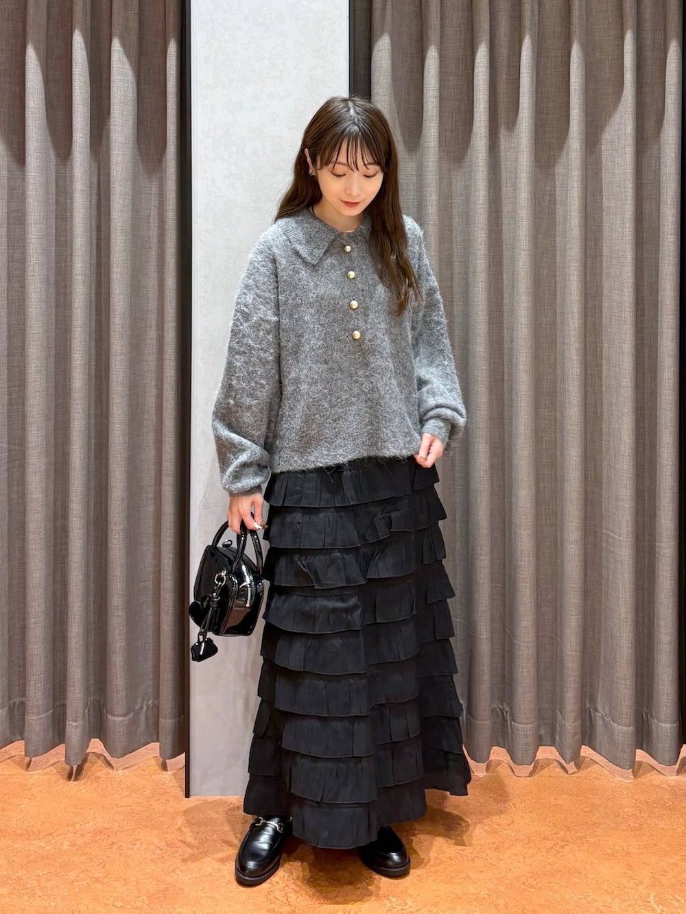 ブラック系のスカート、ブラック系のローファー、ブラック系のボストンバッグを着用したレディースの秋コーディネートの2枚目の写真