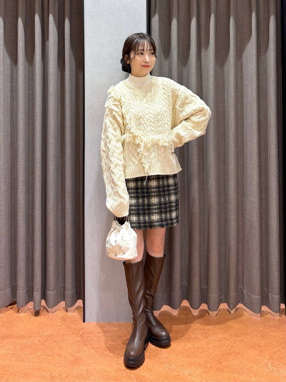 ブラウン系のステンカラーコート、ホワイト系のニット/セーター、ブラウン系のブーツを着用したレディースの冬コーディネートの5枚目の写真