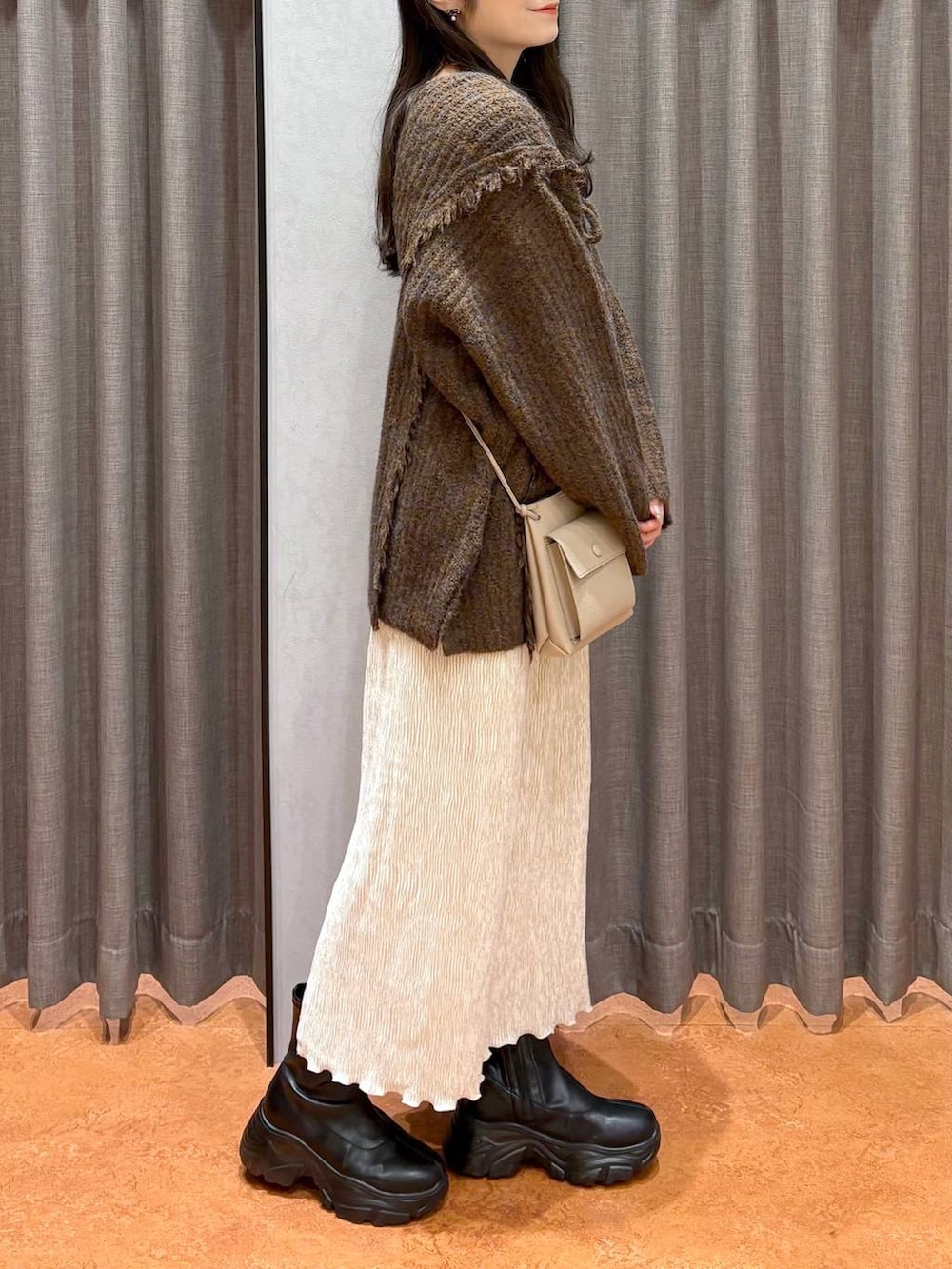 ブラウン系のニット/セーター、ホワイト系のTシャツ/カットソー、ブラック系のブーツを着用したレディースの冬コーディネートの3枚目の写真