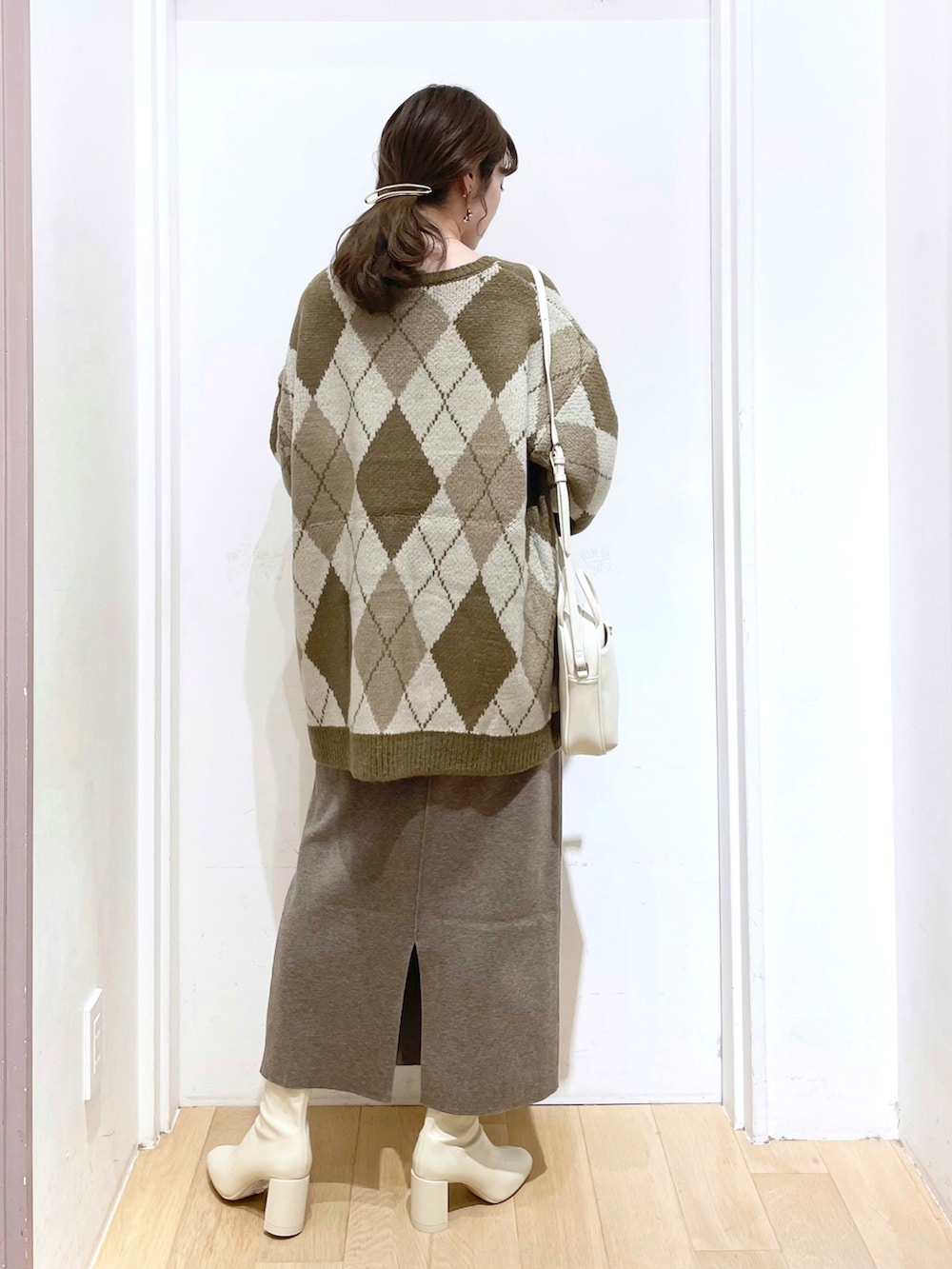 ホワイト系のブーツ、ベージュ系のスカート、ホワイト系のショルダーバッグを着用したレディースの冬コーディネートの2枚目の写真