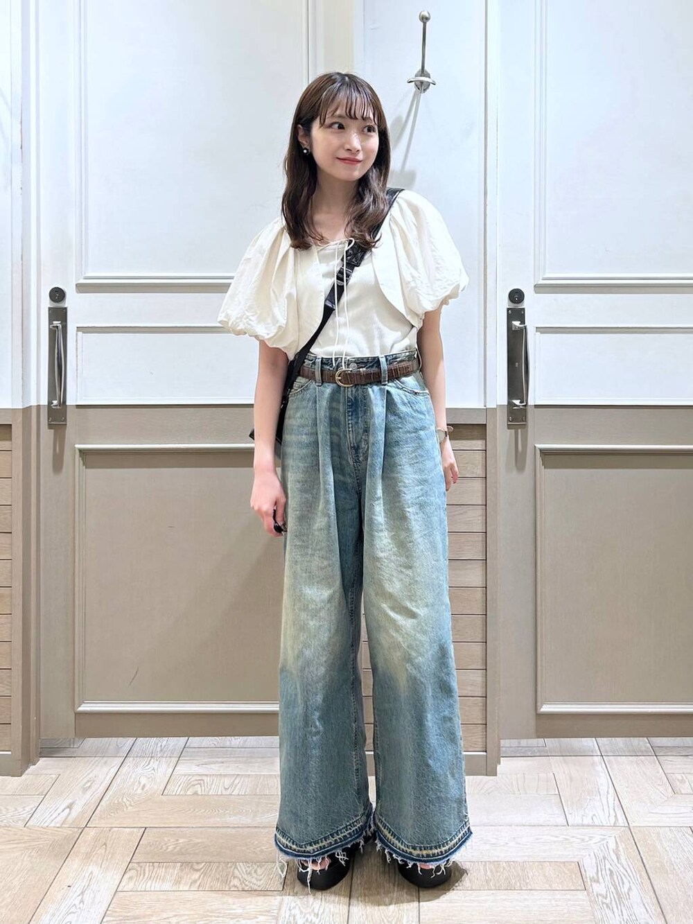 ホワイト系のTシャツ/カットソー、ブラック系のサンダル、ブルー系のデニムパンツを着用したレディースの春コーディネートの2枚目の写真