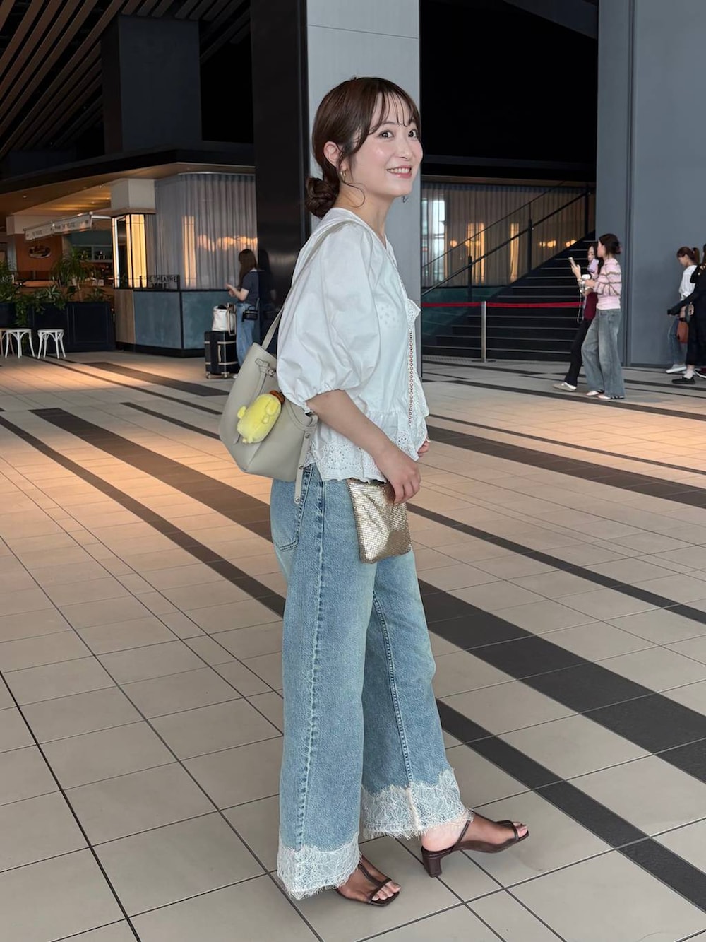 ゴールド系のショルダーバッグ、ブルー系のデニムパンツ、ホワイト系のシャツ/ブラウスを着用したレディースの夏コーディネートの4枚目の写真