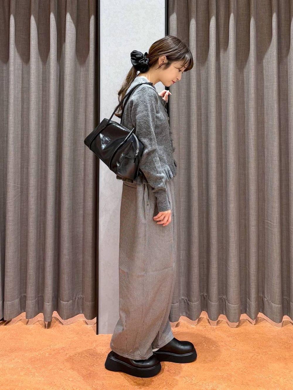 ブラック系のサンダル、ブラック系のボストンバッグ、グレー系のニット/セーターを着用したレディースの秋コーディネートの3枚目の写真