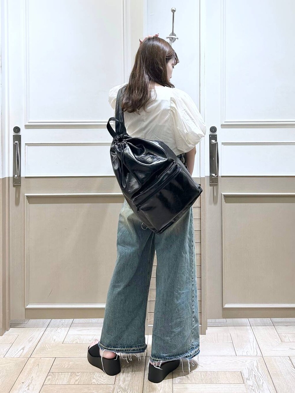 ホワイト系のTシャツ/カットソー、ブラック系のサンダル、ブルー系のデニムパンツを着用したレディースの春コーディネートの7枚目の写真