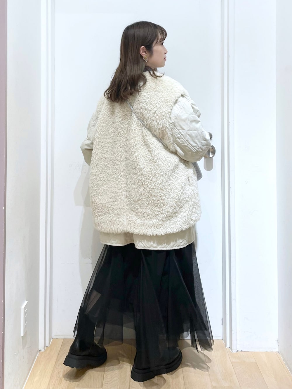 ホワイト系のブルゾン、ブルー系のニット/セーター、シルバー系のショルダーバッグを着用したレディースの冬コーディネートの2枚目の写真