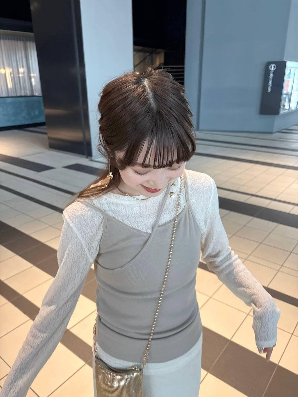 ゴールド系のショルダーバッグ、ホワイト系のスカート、ブラウン系のローファーを着用したレディースの春コーディネートの5枚目の写真