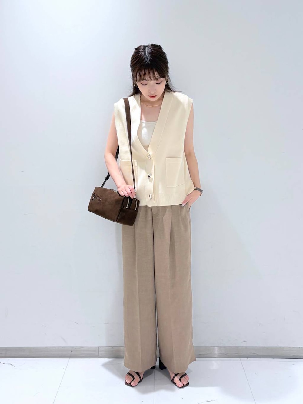 ホワイト系のTシャツ/カットソー、ブラウン系のサンダル、ベージュ系のスラックスを着用したレディースの夏コーディネートの2枚目の写真