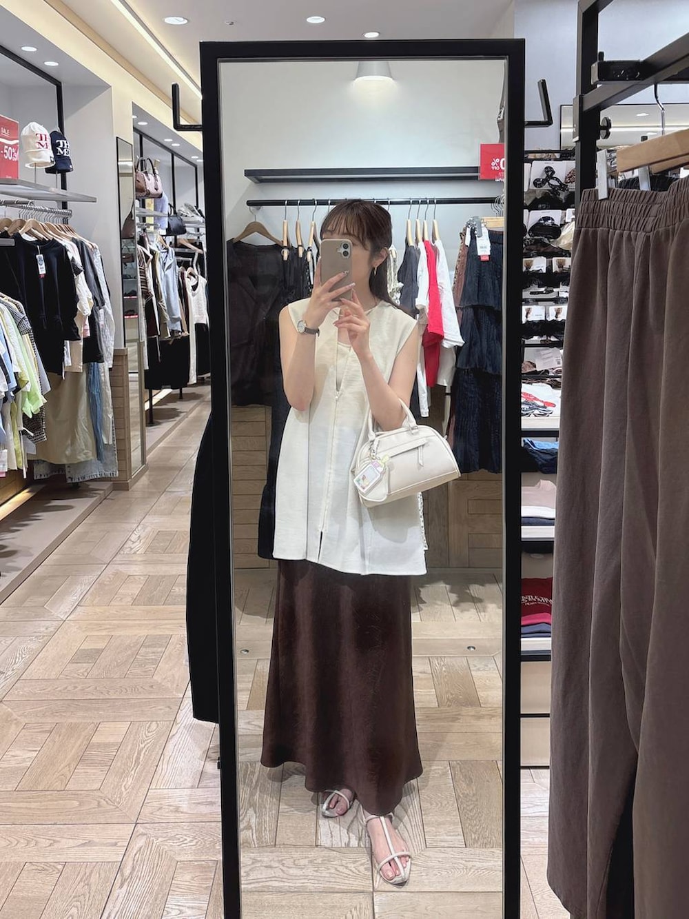 ホワイト系のTシャツ/カットソー、ホワイト系のベスト、ブラウン系のスカートを着用したレディースの夏コーディネートの3枚目の写真