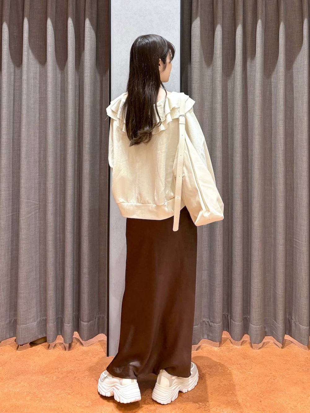 ホワイト系のショルダーバッグ、ベージュ系のスニーカー、ブラウン系のスカートを着用したレディースの冬コーディネートの3枚目の写真