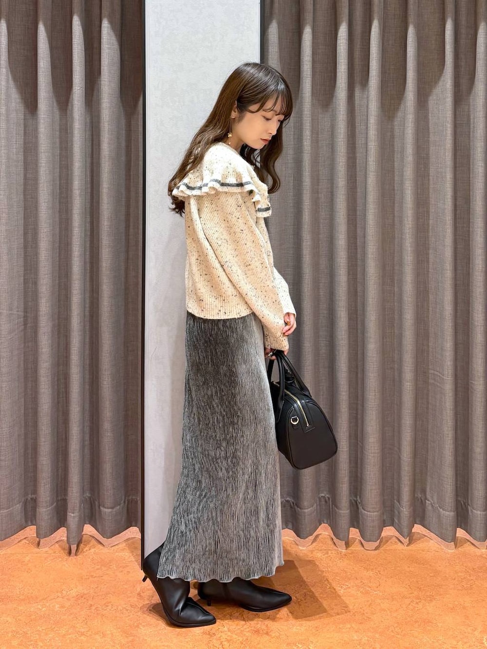 ブラック系のショルダーバッグ、ベージュ系のニット/セーター、グレー系のスカートを着用したレディースの秋コーディネートの4枚目の写真