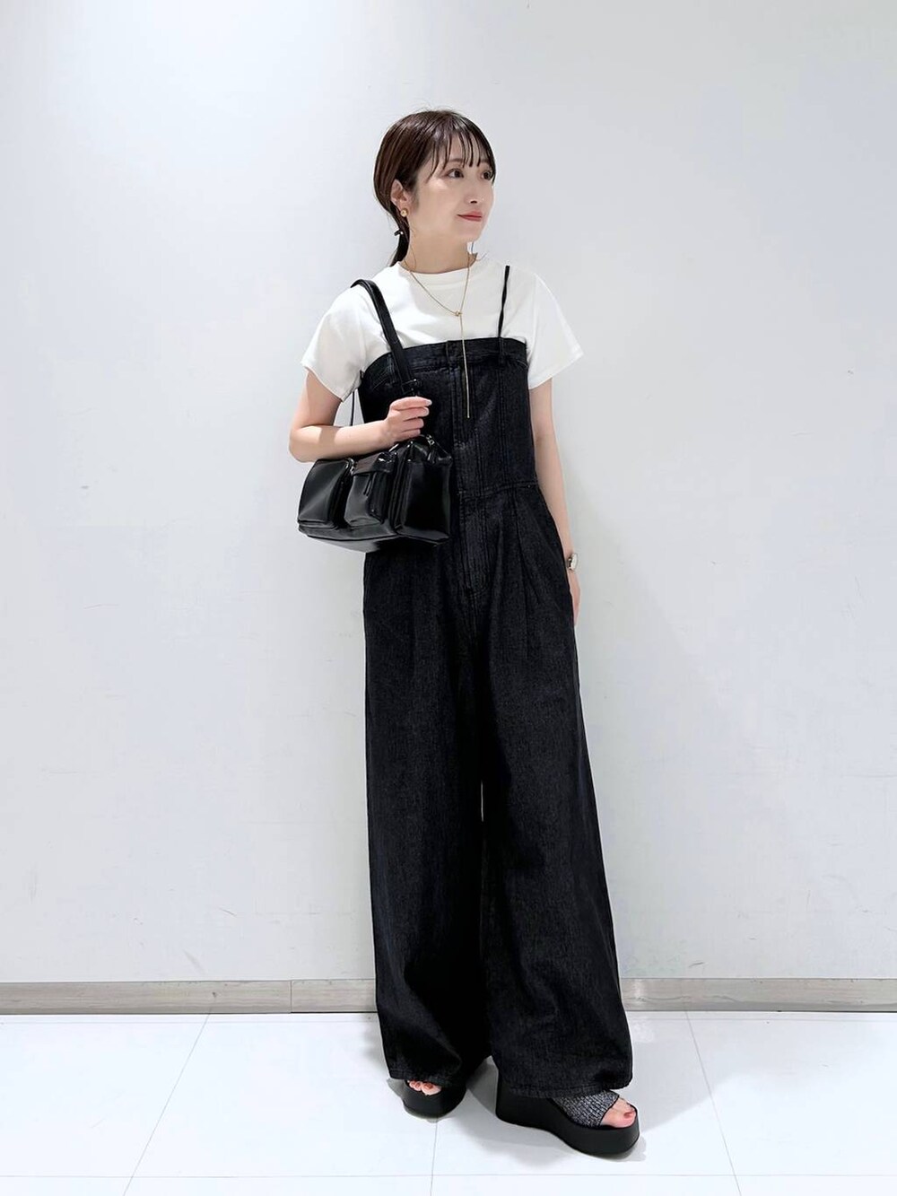 ブラック系のサンダル、ホワイト系のTシャツ/カットソー、ブラック系のボストンバッグを着用したレディースの夏コーディネートの2枚目の写真