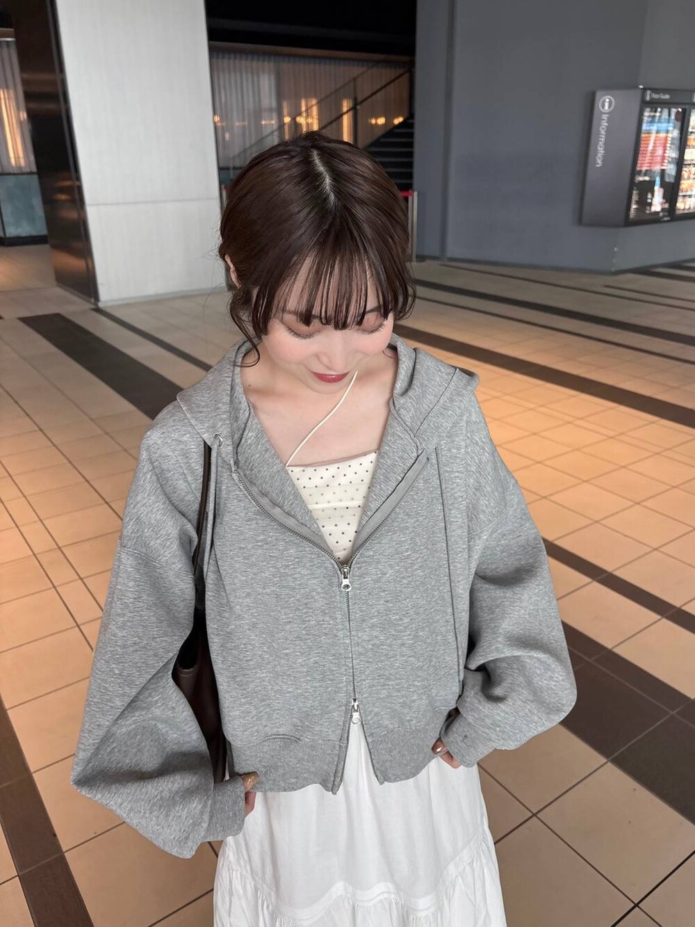 グレー系のパーカー、ブラウン系のトートバッグ、ホワイト系のパンプスを着用したレディースの春コーディネートの6枚目の写真