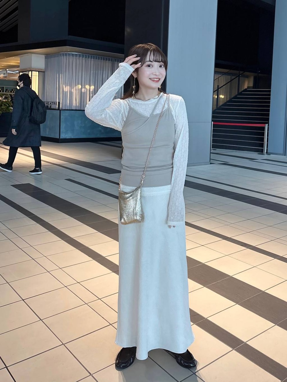 ゴールド系のショルダーバッグ、ホワイト系のスカート、ブラウン系のローファーを着用したレディースの春コーディネートの2枚目の写真