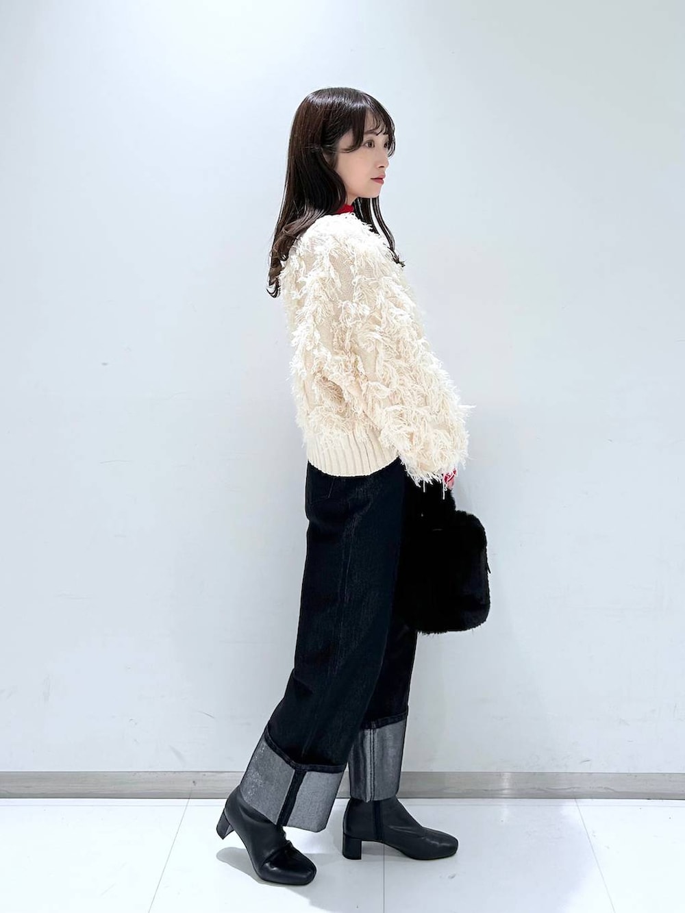 レッド系のニット/セーター、ブラック系のブーツ、ブラック系のショルダーバッグを着用したレディースの冬コーディネートの3枚目の写真