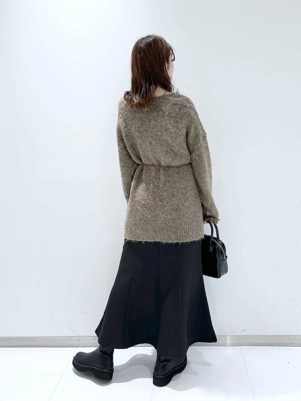 ホワイト系のTシャツ/カットソー、ブラック系のブーツ、ブラック系のスカートを着用したレディースの秋コーディネートの4枚目の写真