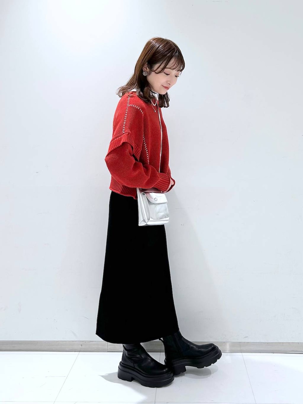 シルバー系のショルダーバッグ、グレー系のニット/セーター、レッド系のTシャツ/カットソーを着用したレディースの秋コーディネートの3枚目の写真