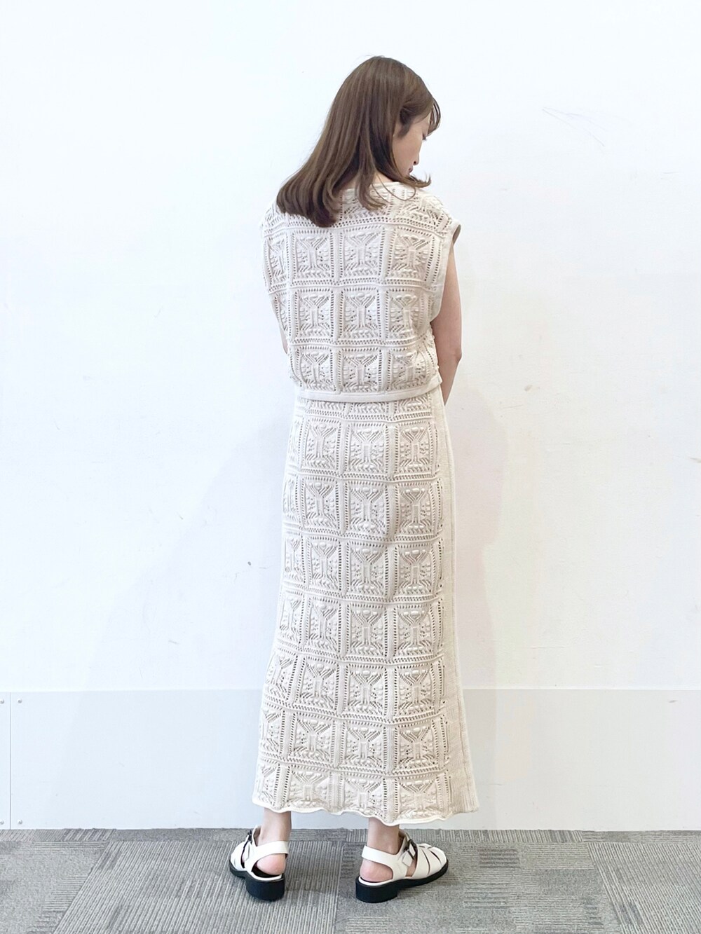 オレンジ系のショルダーバッグ、ホワイト系のサンダル、ホワイト系のスカートを着用したレディースの夏コーディネートの2枚目の写真