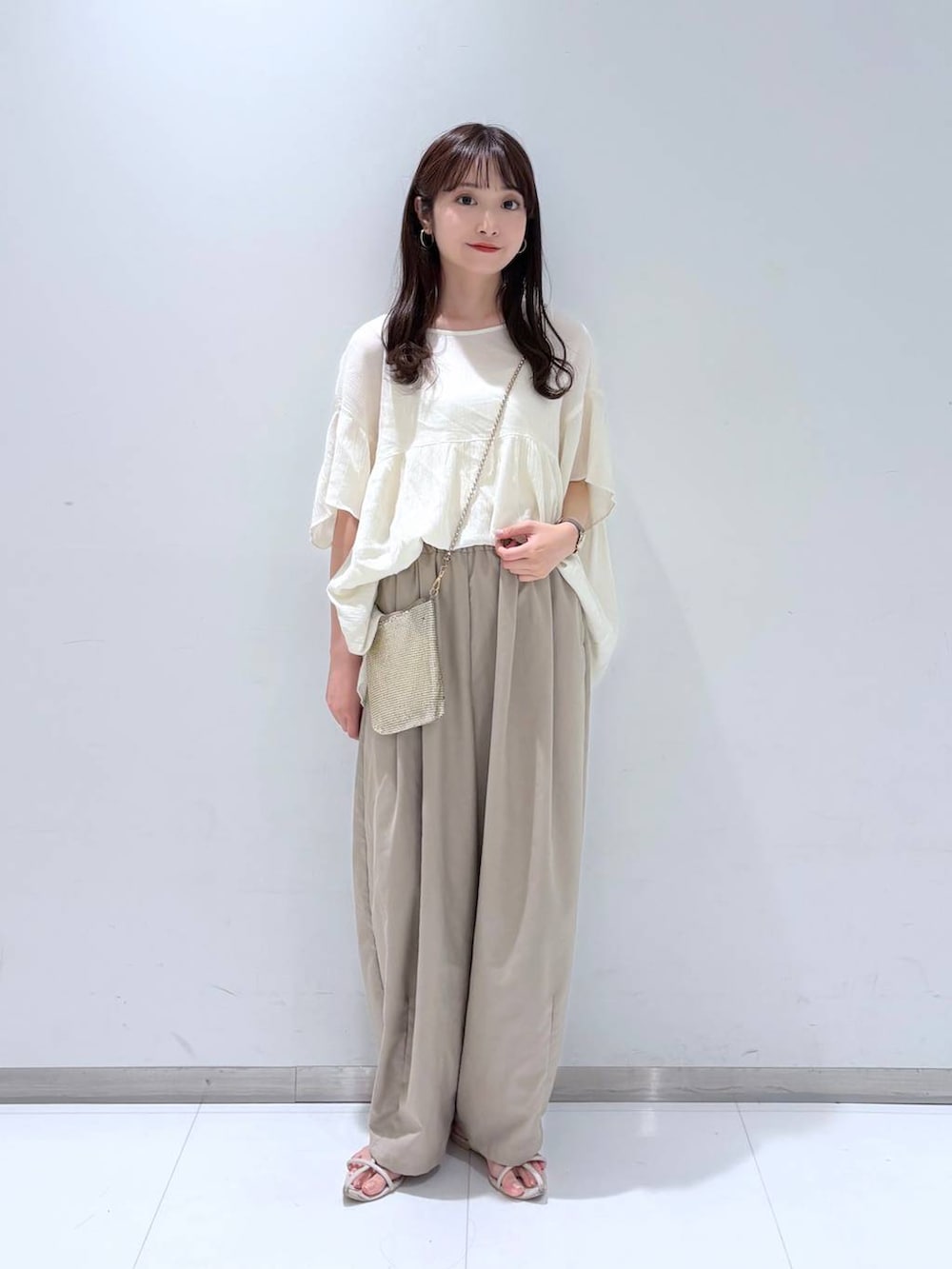 ゴールド系のショルダーバッグ、ホワイト系のサンダル、ベージュ系のその他パンツを着用したレディースの夏コーディネートの2枚目の写真