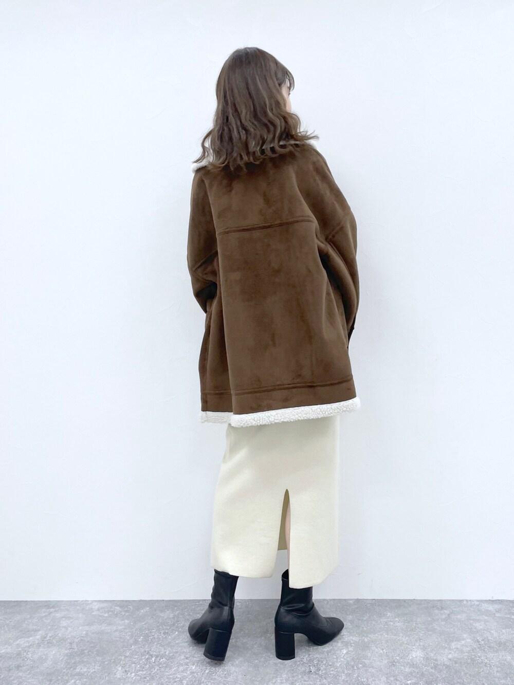 ホワイト系のTシャツ/カットソー、ブラウン系のムートンコート、ブラック系のブーツを着用したレディースの冬コーディネートの2枚目の写真