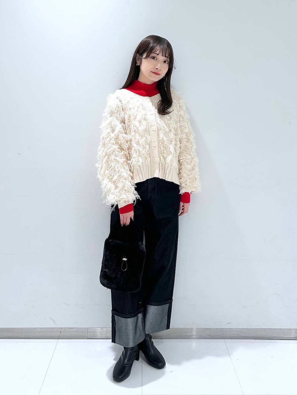 レッド系のニット/セーター、ブラック系のブーツ、ブラック系のショルダーバッグを着用したレディースの冬コーディネートの2枚目の写真