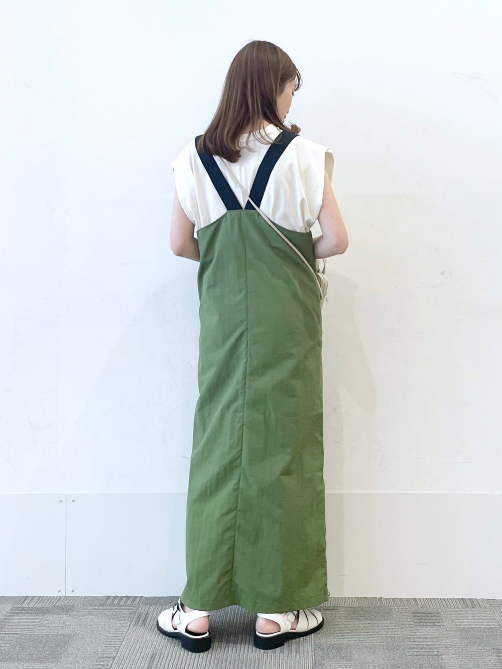 ホワイト系のサンダル、グリーン系のジャンパースカート、ホワイト系のショルダーバッグを着用したレディースの夏コーディネートの2枚目の写真