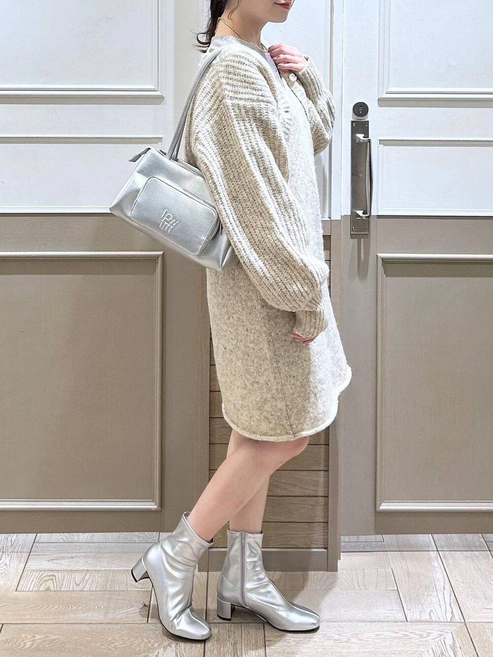 シルバー系のショルダーバッグ、ホワイト系のTシャツ/カットソー、シルバー系のブーツを着用したレディースの冬コーディネートの2枚目の写真
