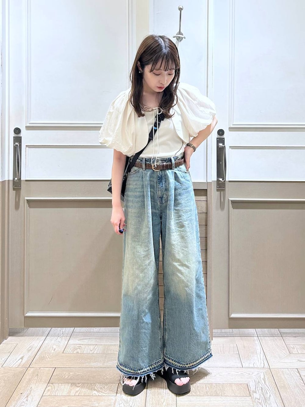 ホワイト系のTシャツ/カットソー、ブラック系のサンダル、ブルー系のデニムパンツを着用したレディースの春コーディネートの4枚目の写真