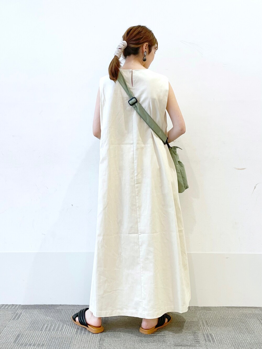 ブラック系のサンダル、ホワイト系のワンピース、グリーン系のショルダーバッグを着用したレディースの夏コーディネートの2枚目の写真