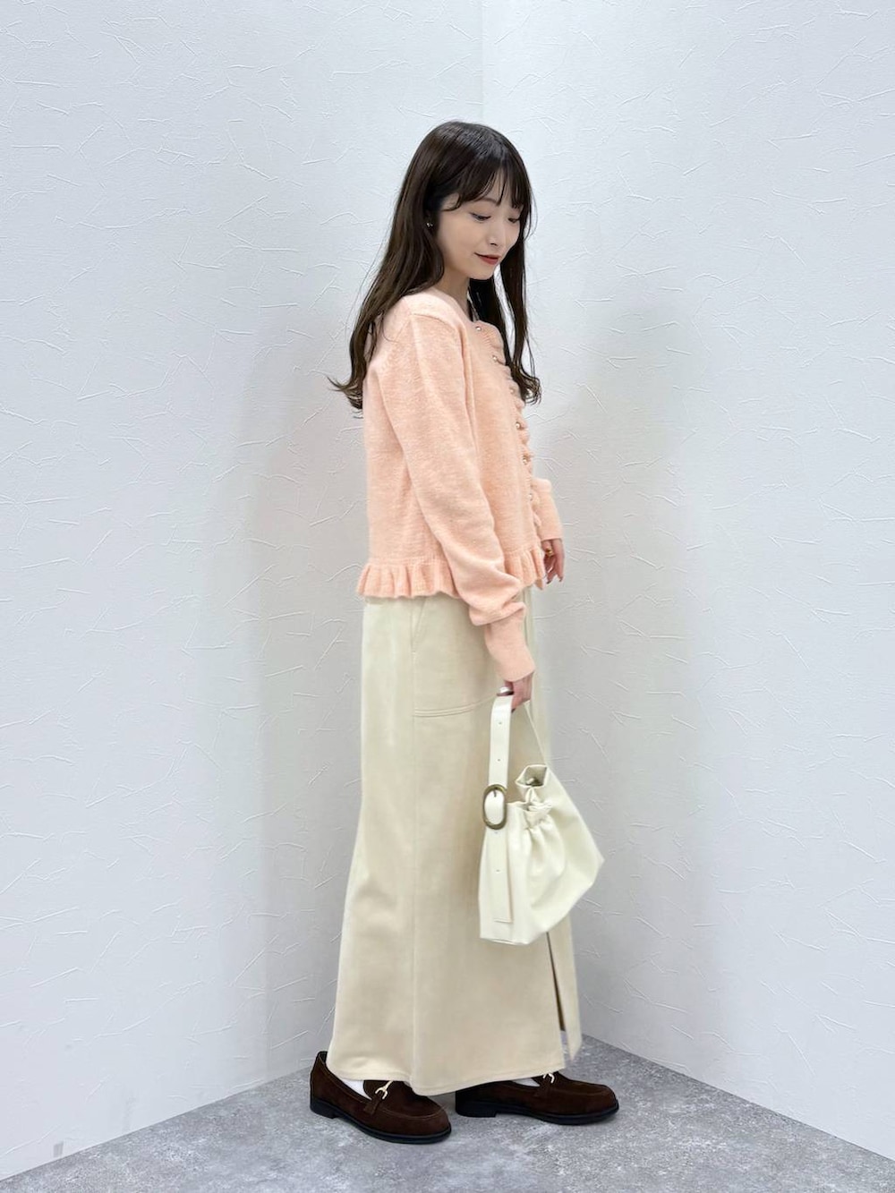 ホワイト系のスカート、ブラウン系のローファー、ホワイト系のショルダーバッグを着用したレディースの秋コーディネートの3枚目の写真