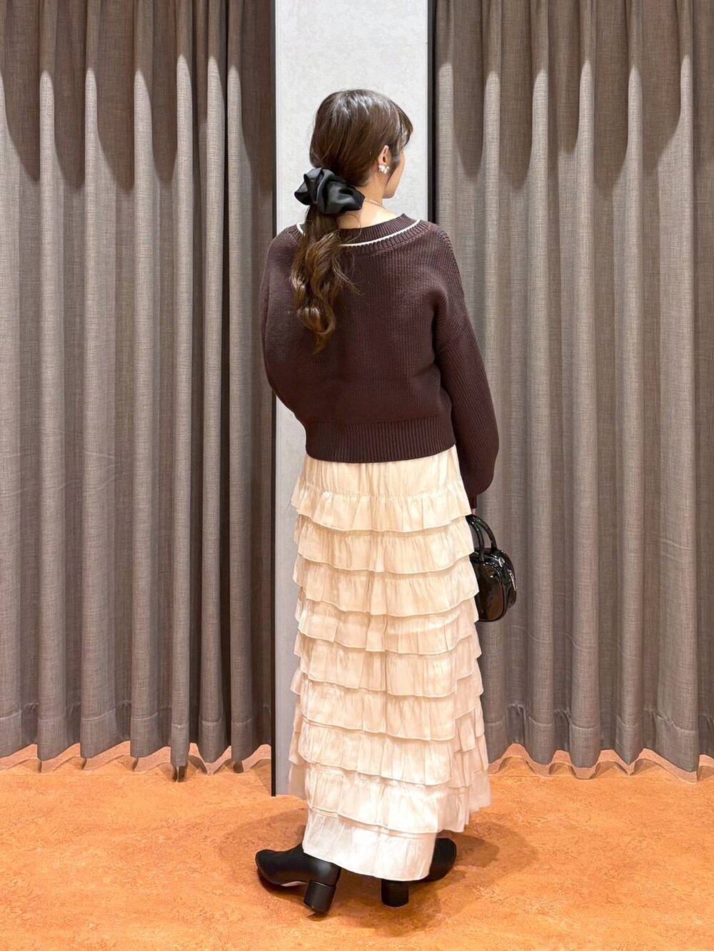 ベージュ系のキャミソール、ブラウン系のカーディガン/ボレロ、ブラック系のボストンバッグを着用したレディースの秋コーディネートの4枚目の写真