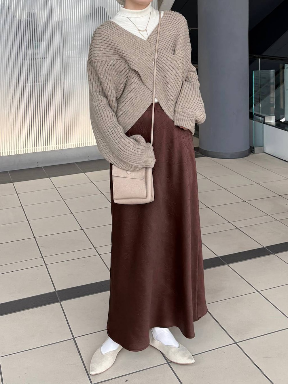 ブラウン系のスカート、ホワイト系のパンプス、ベージュ系のヘアゴムを着用したレディースの冬コーディネートの2枚目の写真