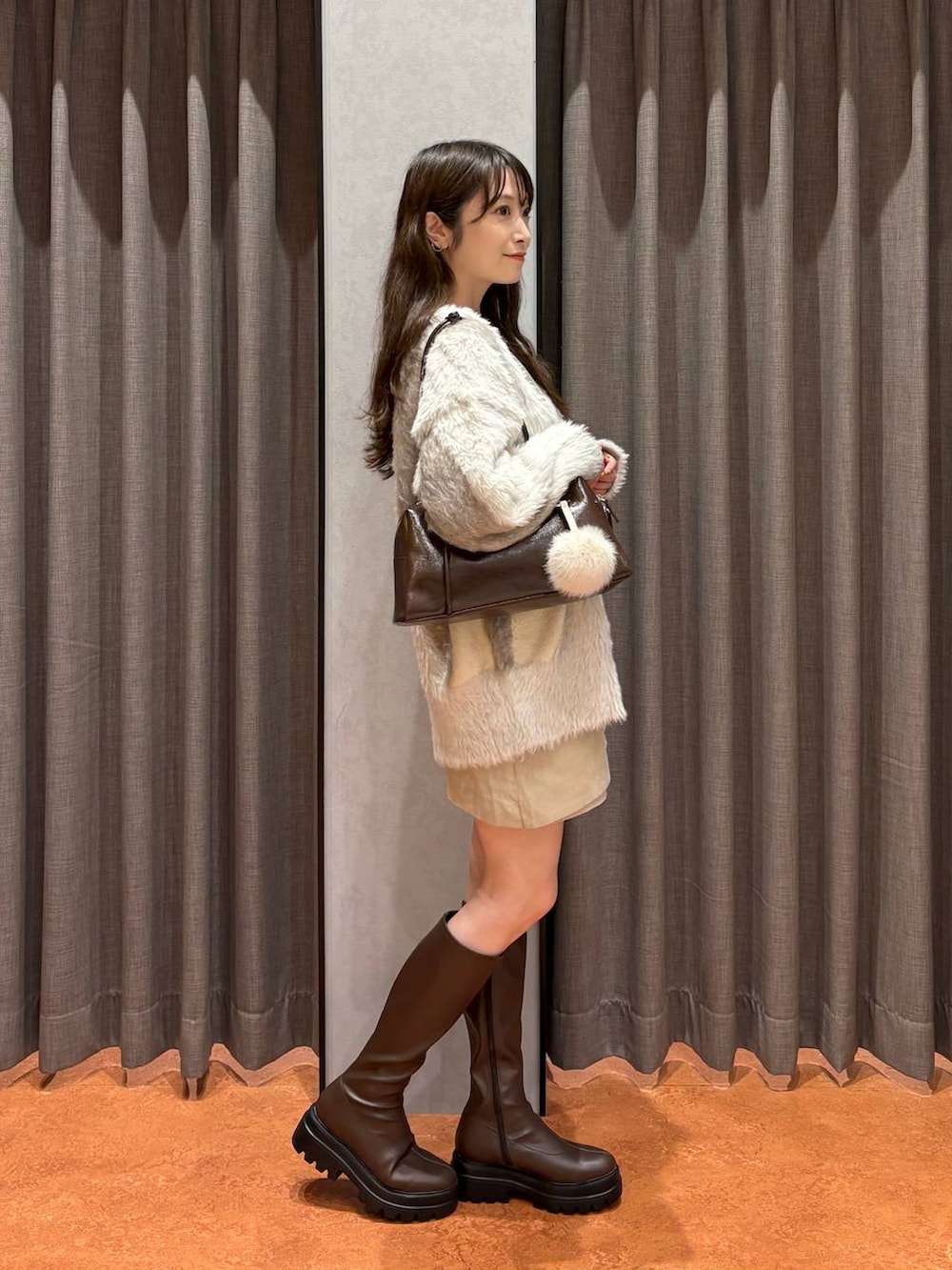 ホワイト系のカーディガン/ボレロ、ホワイト系のスカート、ブラウン系のブーツを着用したレディースの秋コーディネートの3枚目の写真