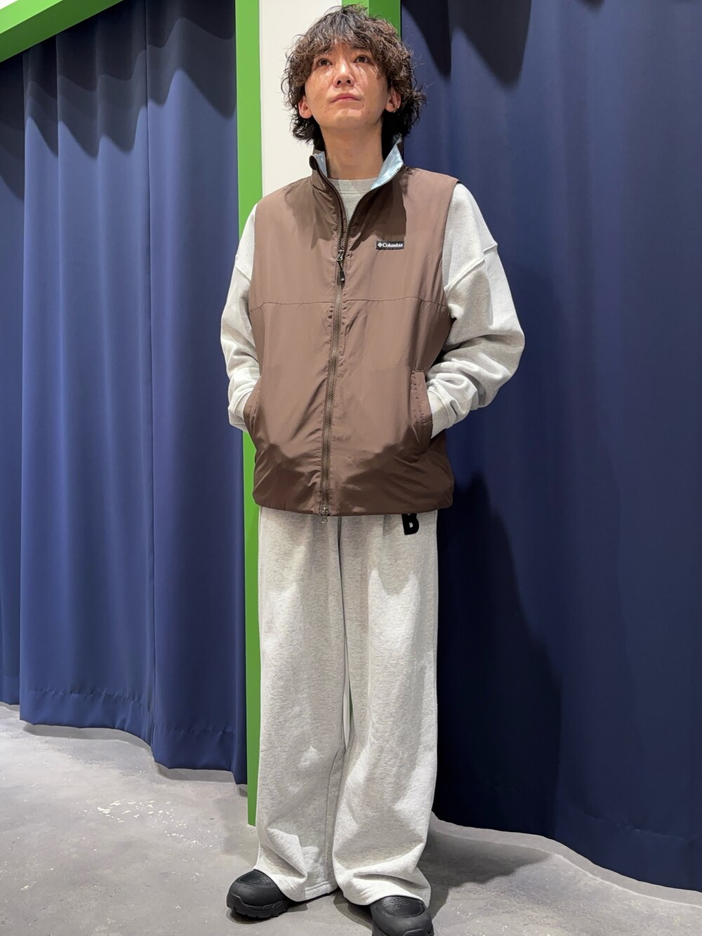 グレー系のスウェット、グレー系のスウェットパンツ、ブラウン系のベストを着用したメンズの冬コーディネートの2枚目の写真