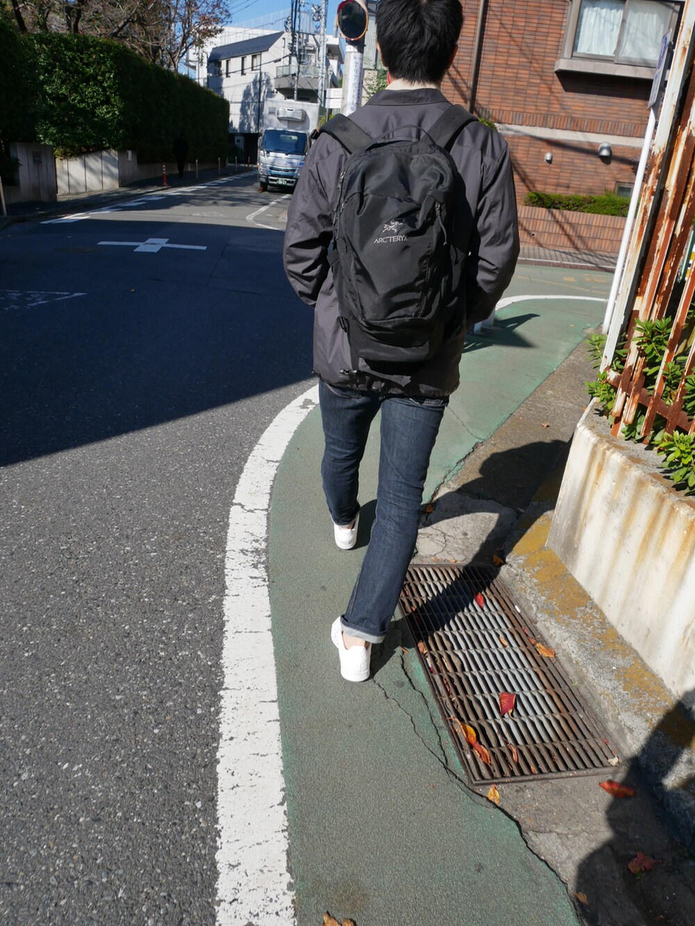 ブラック系のデニムパンツ、ブラック系のブルゾン、ホワイト系のスニーカーを着用したメンズの秋コーディネートの3枚目の写真