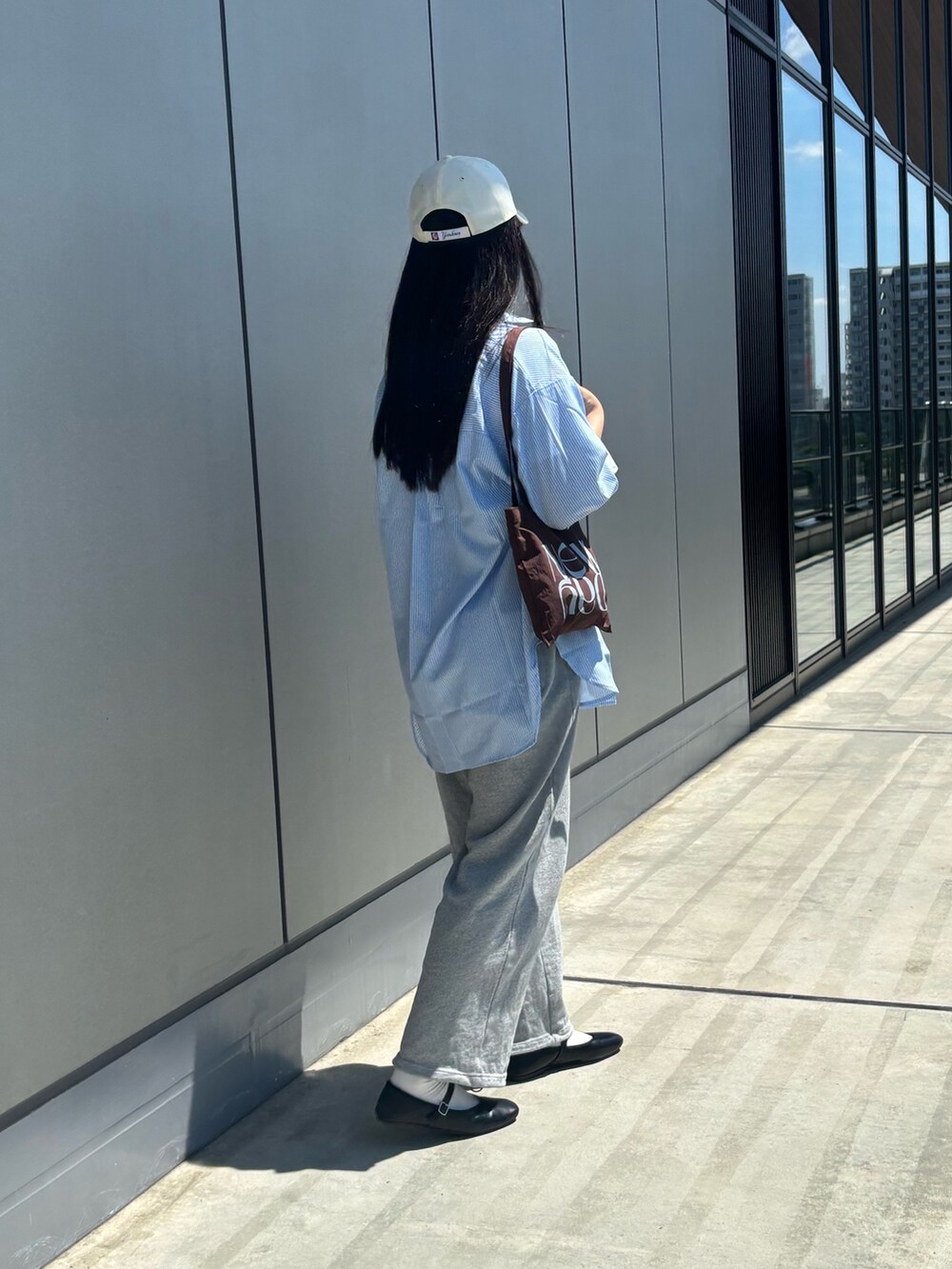 グレー系のスウェットパンツ、ホワイト系のTシャツ/カットソー、ブラウン系のトートバッグを着用したレディースの夏コーディネートの5枚目の写真