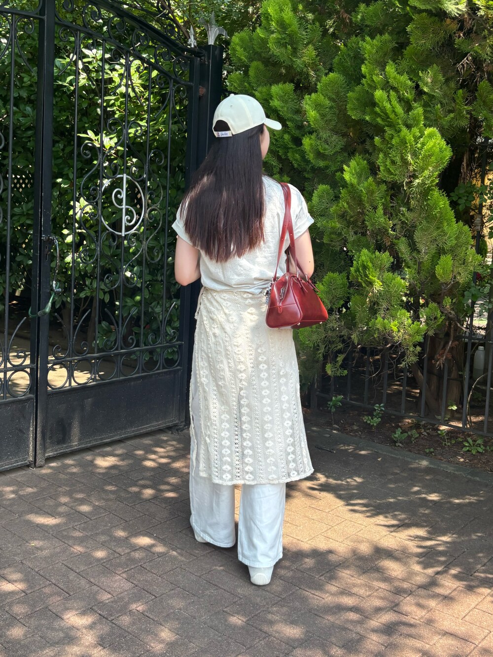 グレー系のTシャツ/カットソー、ホワイト系のデニムパンツ、レッド系のボストンバッグを着用したレディースの夏コーディネートの3枚目の写真