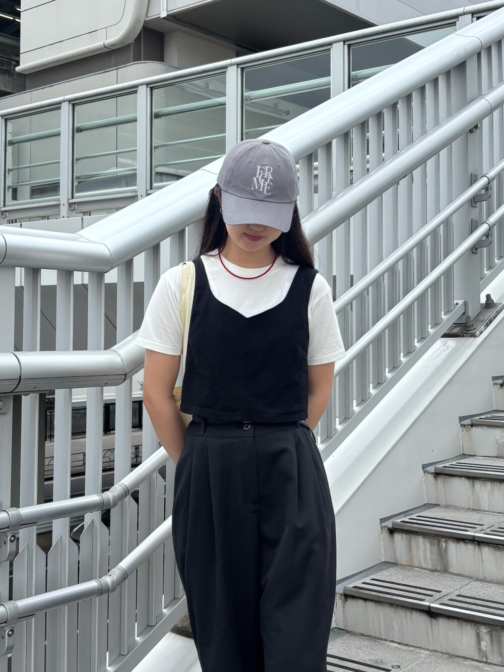 ホワイト系のTシャツ/カットソー、ブラック系のベスト、ホワイト系のトートバッグを着用したレディースの夏コーディネートの3枚目の写真