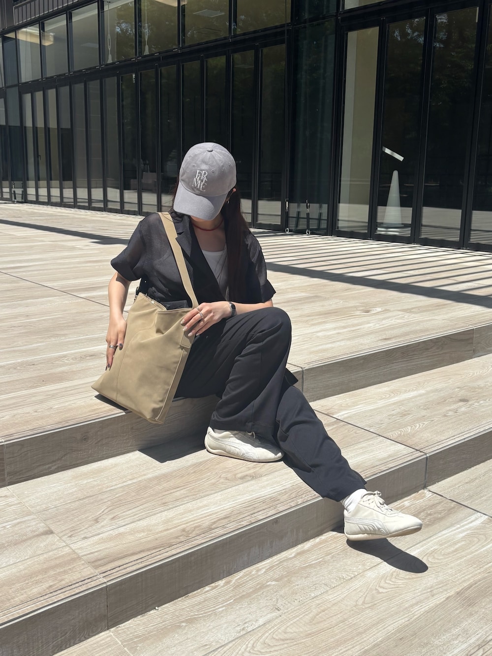 ブラック系のテーラードジャケット、ホワイト系のキャミソール、ブラック系のスラックスを着用したレディースの夏コーディネートの3枚目の写真